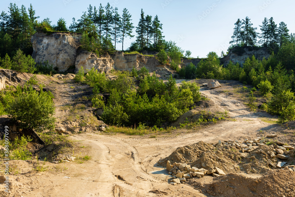 Limestone quarry landscape view. Hillside wall, dirt roads and some trees. Mine in Jozefow, Poland, Europe.