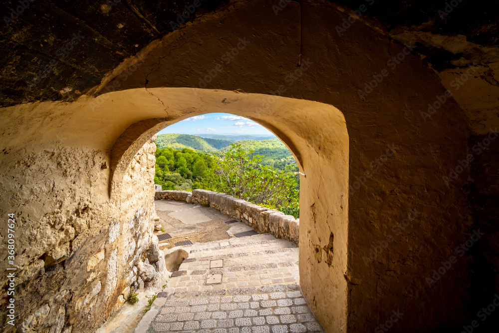 View through a stone arched passage at the medieval hilltop village of Tourrettes-sur-Loup, France of the Alpes-Maritimes mountains of Southern France