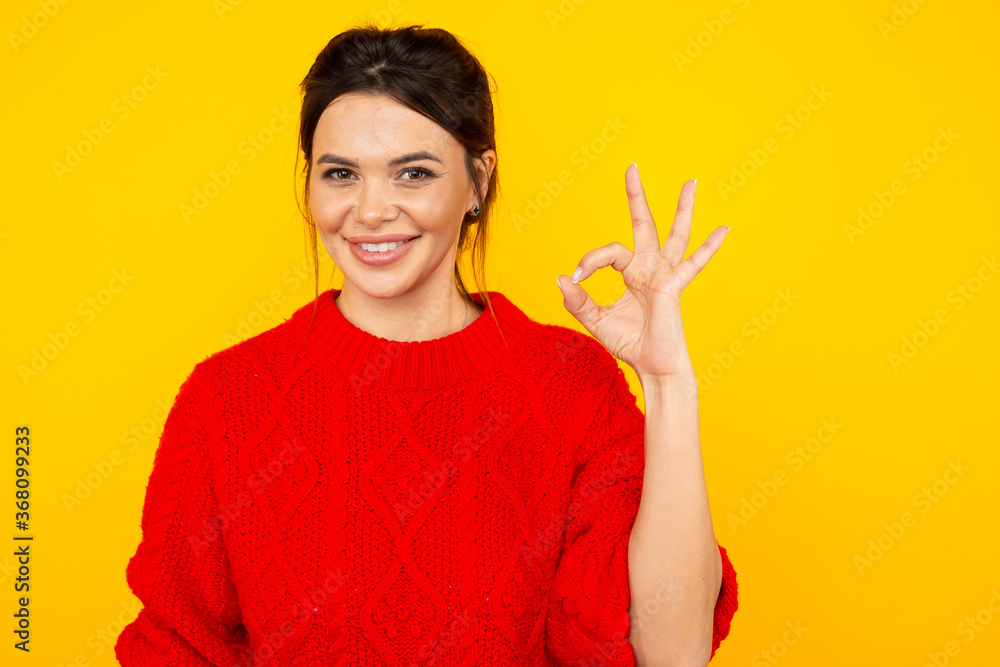 Woman in the bright colored sweater showing ok sign Woman in the bright colored sweater showing ok sign