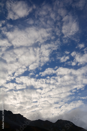夕暮れ時のうろこ雲と濃い青空、北アルプス、剱岳界隈から見る、遠くの山並み。スカイライン。稜線。断崖絶壁。山肌。The clouds & skyline in the nothern alps.日本アルプス。山脈。絶景。山岳地帯。縦走。縦写真。 © Sanae