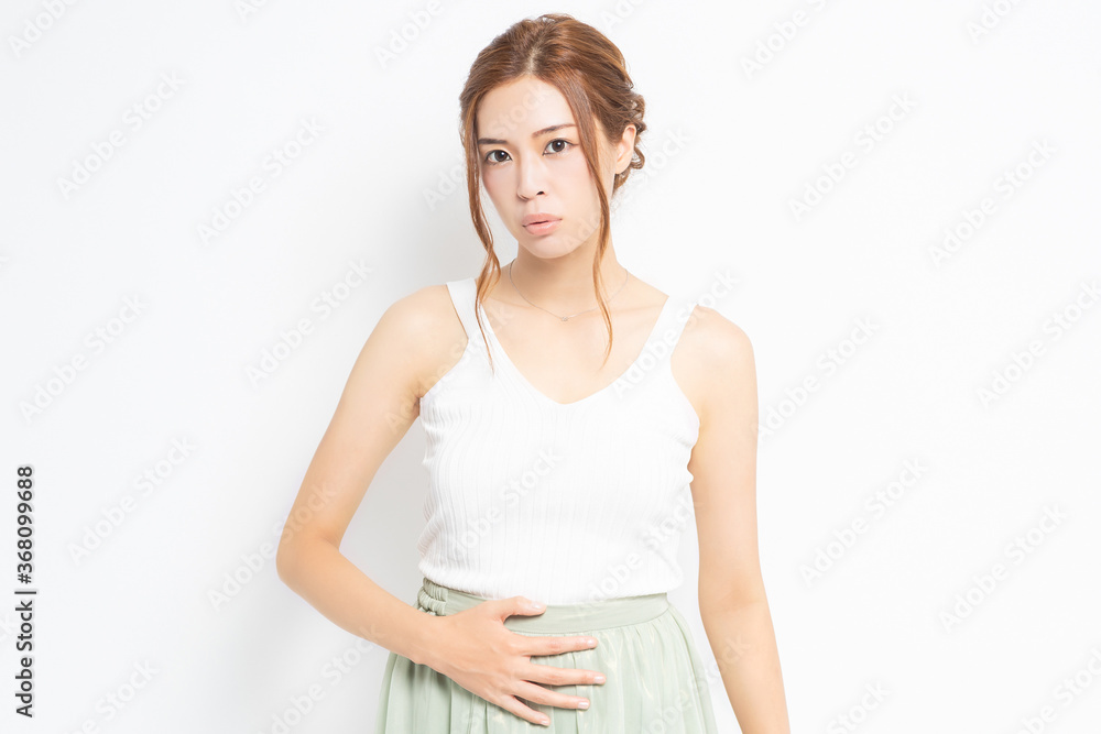 お腹に手を当てる白い服を着た若い女性 お腹に手を当てる白い服を着た若い女性