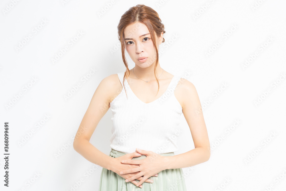 お腹に手を当てる白い服を着た若い女性 お腹に手を当てる白い服を着た若い女性
