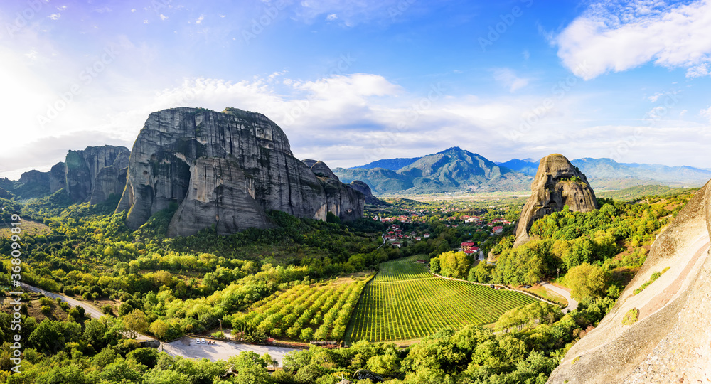 Panoramic views of the valley in the foothills of the mountain formations in Meteora, the monastery vineyard in the foreground and the city of Kastraki in the background.