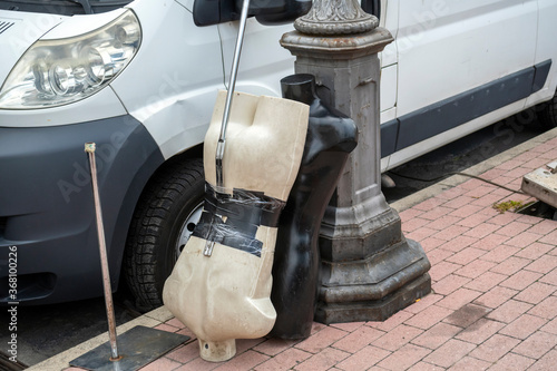 Two oddly placed male mannequin torsos, one black and one white, are balanced on a sidewalk in Ventimiglia, Italy