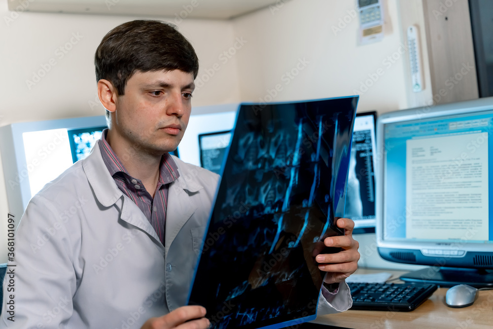 Doctor reading x-ray film. Selective focus. Portrait of radiologist at working place. Doctor reading x-ray film. Selective focus. Portrait of radiologist at working place.