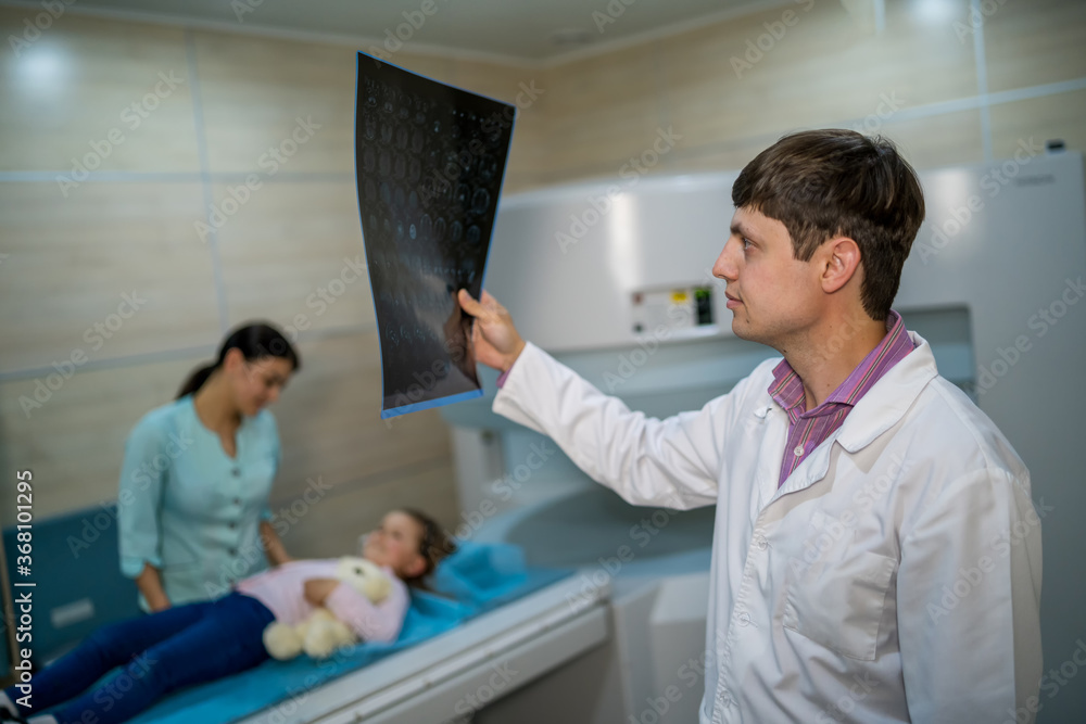 Fototapeta premium Mature male doctor looking at x-ray isolated on modern office backgound. Healthcare, roentgen, people and medicine concept.