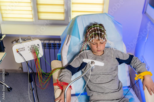 Boy in a special cap during electroencephalography next to the monitor with readings. photo