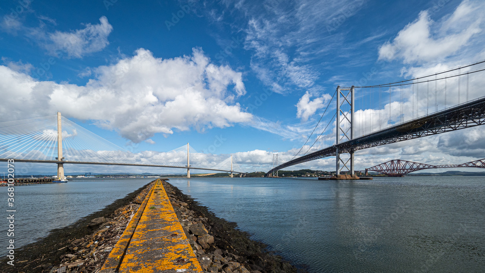 Obraz premium The Forth Bridges near Edinburgh in Scotland. Towering side by side over the Firth of Forth, these structures represent Scottish engineering over three centuries