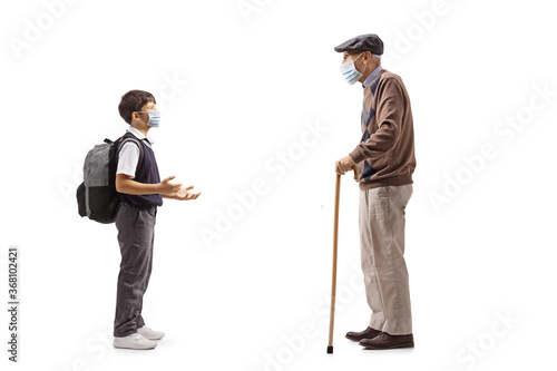 Schoolboy talking to his grandfather and wearing a protective face mask