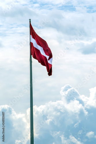 Flag of Latvia against the sky. Red-white flag.
