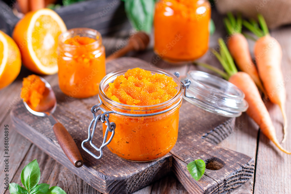 Carrot Jam with orange juice in a glass jar on a wooden table, ingredients on a wooden board Carrot Jam with orange juice in a glass jar on a wooden table, ingredients on a wooden board