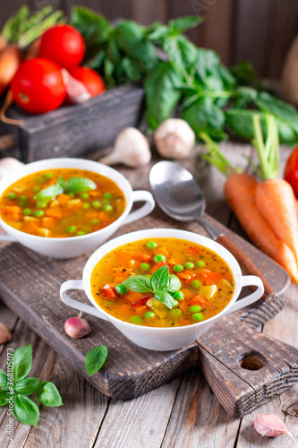 Vegetable soup in a white bowl on a wooden board on the table. Vegetarian soup.