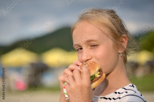 girl eating hamburger on beach