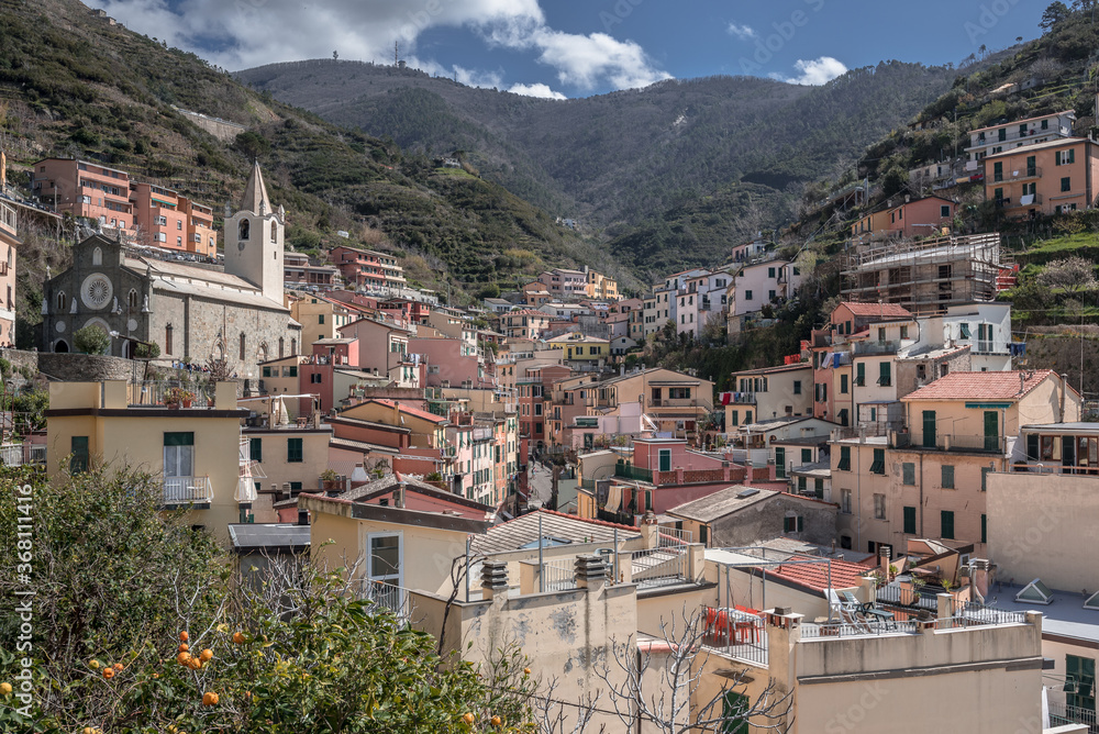 View of Riomaggiore village, first & most southern of Cinque Terre coastal villages, located in a small & narrow valley, as seen from west seaside towards east, La Spezia, Liguria region, Italy.