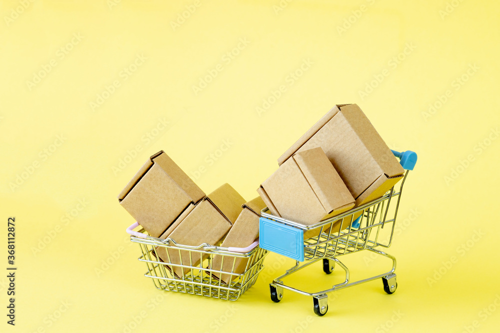 Paper shopping bags in a shopping cart on yellow background, concept online shopping.