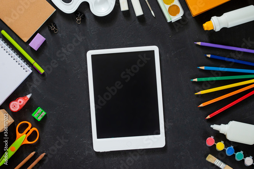 School supplies on black board background. Back to school concept. Frame, flatlay, copy space for text. mock up, tablet