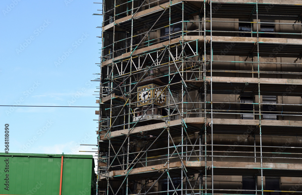Old Ornate Clock Surrounded by Scaffolding on Building under Renovation 