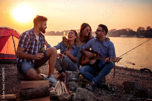 Young people enjoying in music on camping trip.