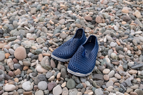 Blue rubber bathing slippers. Beach shoes on pebbles, near the sea.