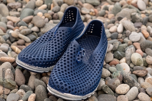 Blue rubber bathing slippers. Beach shoes on pebbles, near the sea.