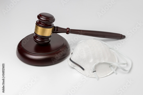 N95 face mask and gavel on white background. Concept of face covering mandate, ordinance, lawsuit, freedom, constitutional rights during Covid-19 coronavirus pandemic
