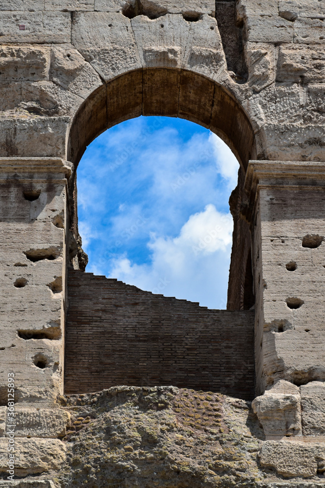 Detail of the famous Italian Colosseum monument in Rome, built in marble, with a blue sky background
