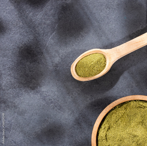 Organic green powder on wooden spoon - text space