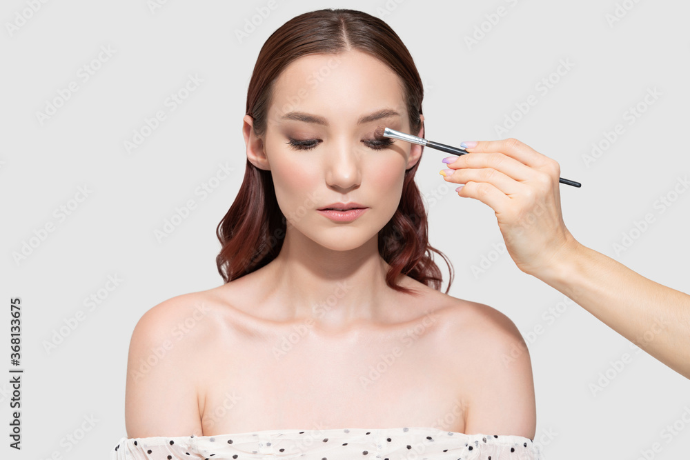 Fototapeta premium Artist Applying Cosmetic On Eyelid Of Caucasian Model