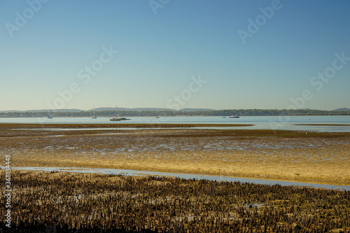 View over low tide sand flats to boats moored in the bay  and islands on the horizon . Redland Bay  Queensland  Australia.