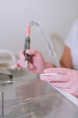 Hand in a pink latex medical gloves. Tools for permanent makeup.