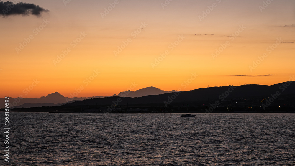Bright orange-yellow sunset in the resort city of Gelendzhik. A colorful summer landscape, a view of the sea Bay, mountains and a passing pleasure yacht. Black sea coast Bright orange-yellow sunset in the resort city of Gelendzhik. A colorful summer landscape, a view of the sea Bay, mountains and a passing pleasure yacht. Black sea coast