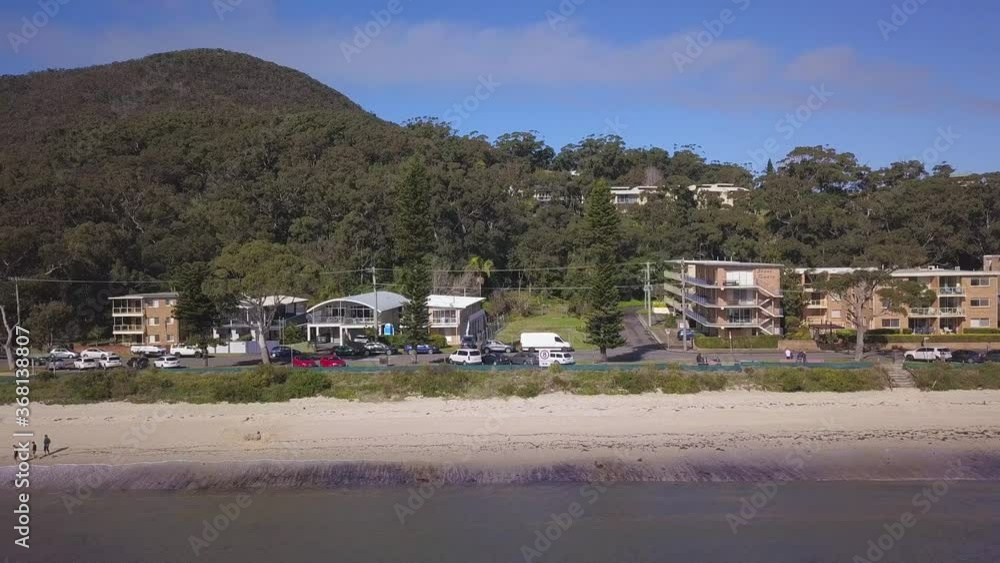 Beautiful aerial pan over the coastal beach with waterfront community houses or properties in a small town of Sydney. Shoal Bay, New South Wales, Australia.