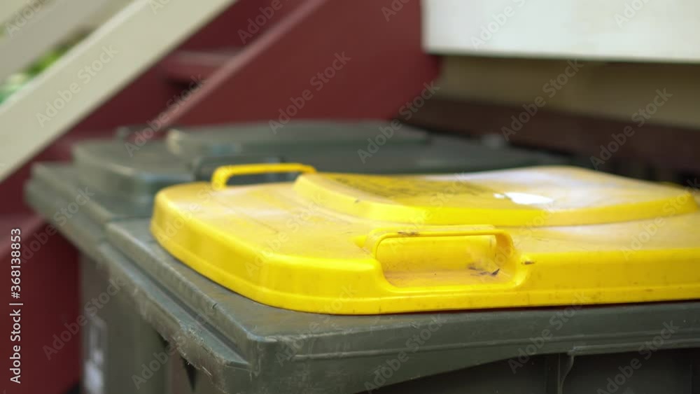 Person puts tin cans in recycle bin with yellow lid, closeup Stock