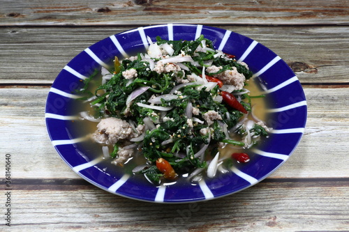 фотографія Spicy salad of cutting fresh young green Paco fern with marinated pork, chilly and sliced shallot seasoning with lime juice and fish sauce on the plate
