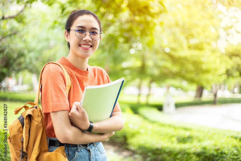 Portrait of nerd Asian woman girl smart teen happy smiling with glasses at green park outdoor in university campus with copyspace Portrait of nerd Asian woman girl smart teen happy smiling with glasses at green park outdoor in university campus with copyspace