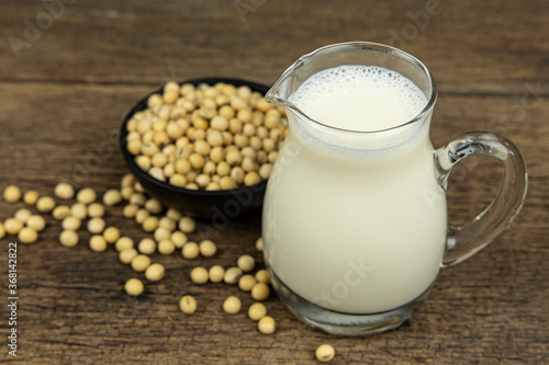 A glass of soymilk with soybeans on wooden table background.