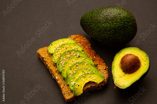 fresh avocado slices on dark rye bread made with fresh sliced avocados and sesame seeds.