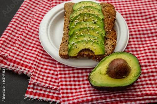 Avocado sandwich on dark rye bread made with fresh sliced avocados and sesame seeds. Yummy and healthy breakfast
