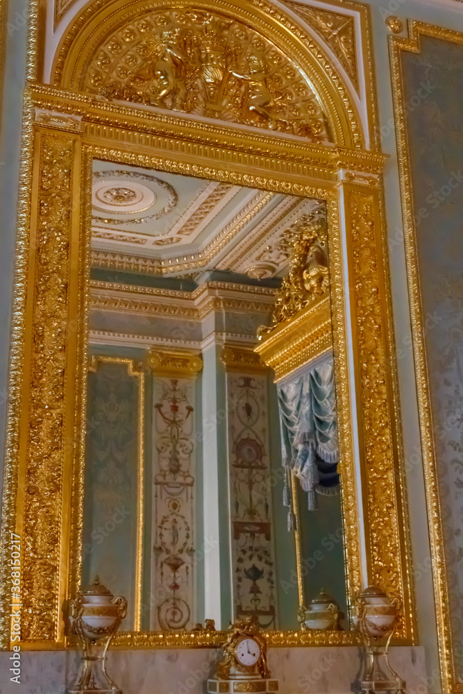 Large mirror in gilded ornate frame on a wall in luxurious room