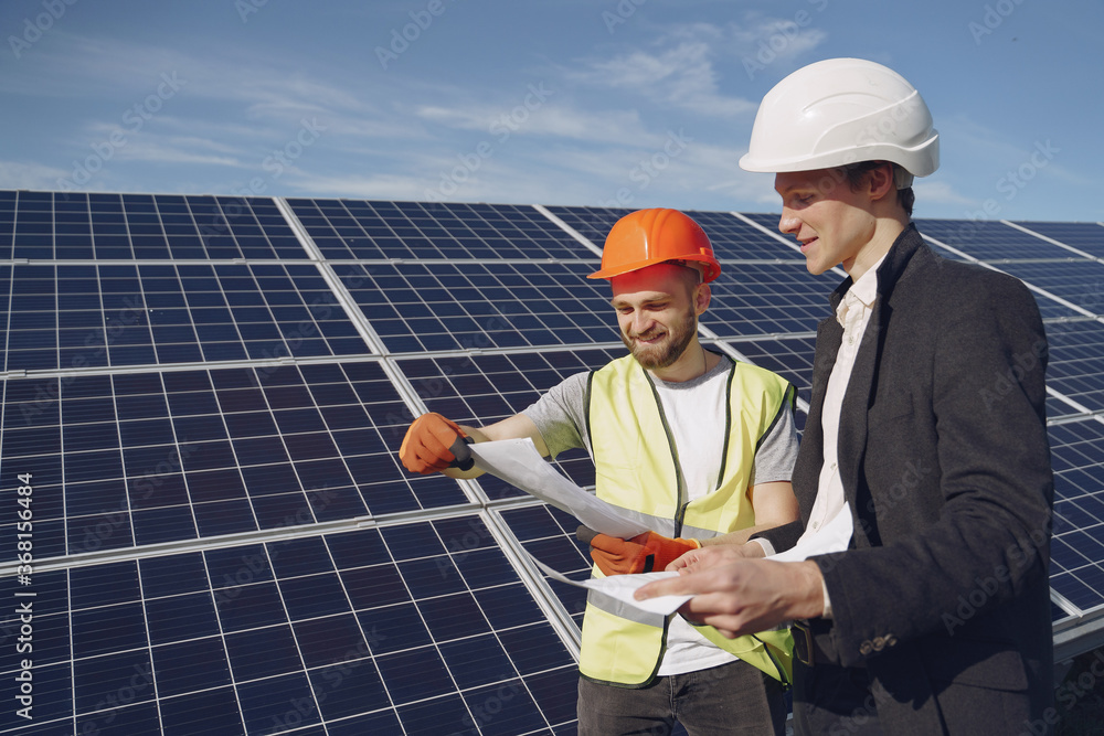 Businessman and worker near solar energy batteries. Business client showing photovoltaic detail to foreman. Two men making deal. Businessman and worker near solar energy batteries. Business client showing photovoltaic detail to foreman. Two men making deal.