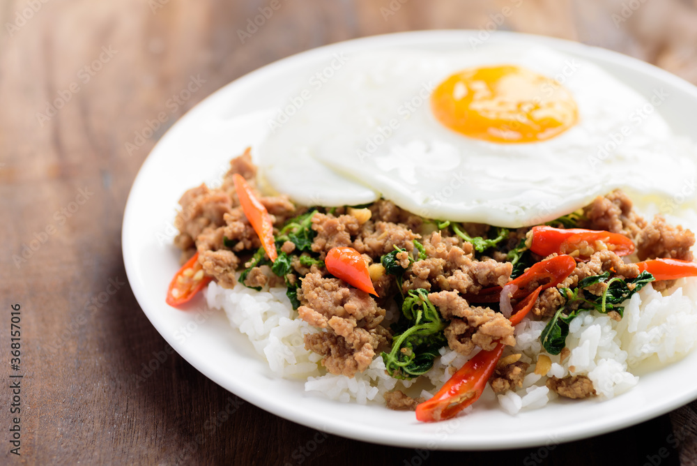 Thai food, Stir-fried holy basil with minced pork and fried egg on top eating with cooked rice (Pad Kaprao Moo Kai Dao)