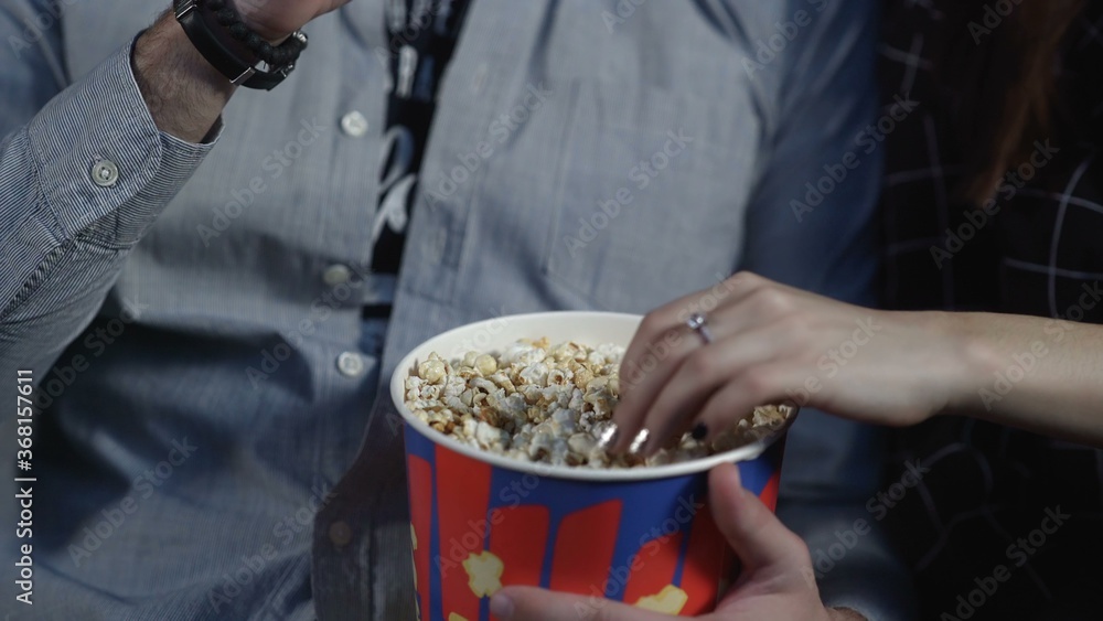 Obraz premium Loving couple are eating popcorn in cinema and watching the movie.