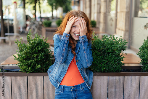 Cute embarrassed young woman covering her face