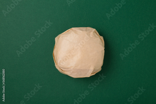 Packed burger on green background, top view. Wrapped hamburger sandwich, blank mock up.