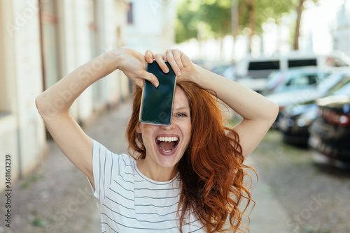 Laughing young woman holding up her mobile