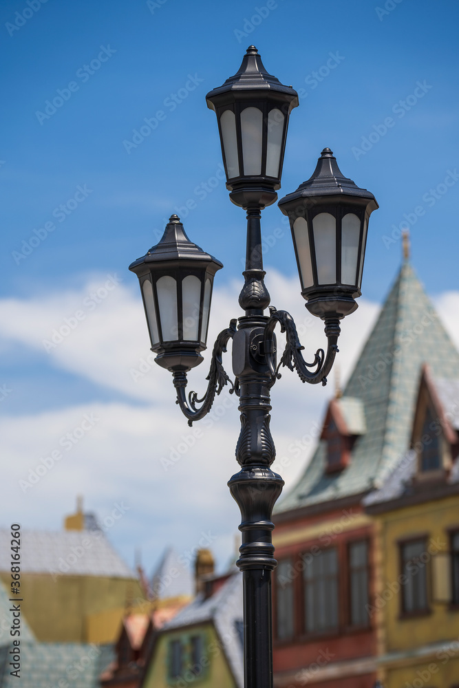 Street lamppost against the old buildings background. Classic victorian street lamps on an old fashioned iron lamp post set