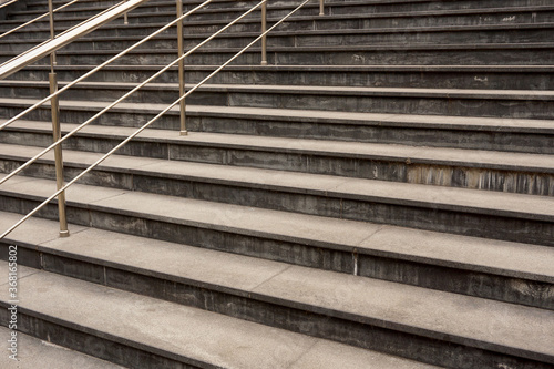 Gray stone staircase with metal railings made of stainless steel.