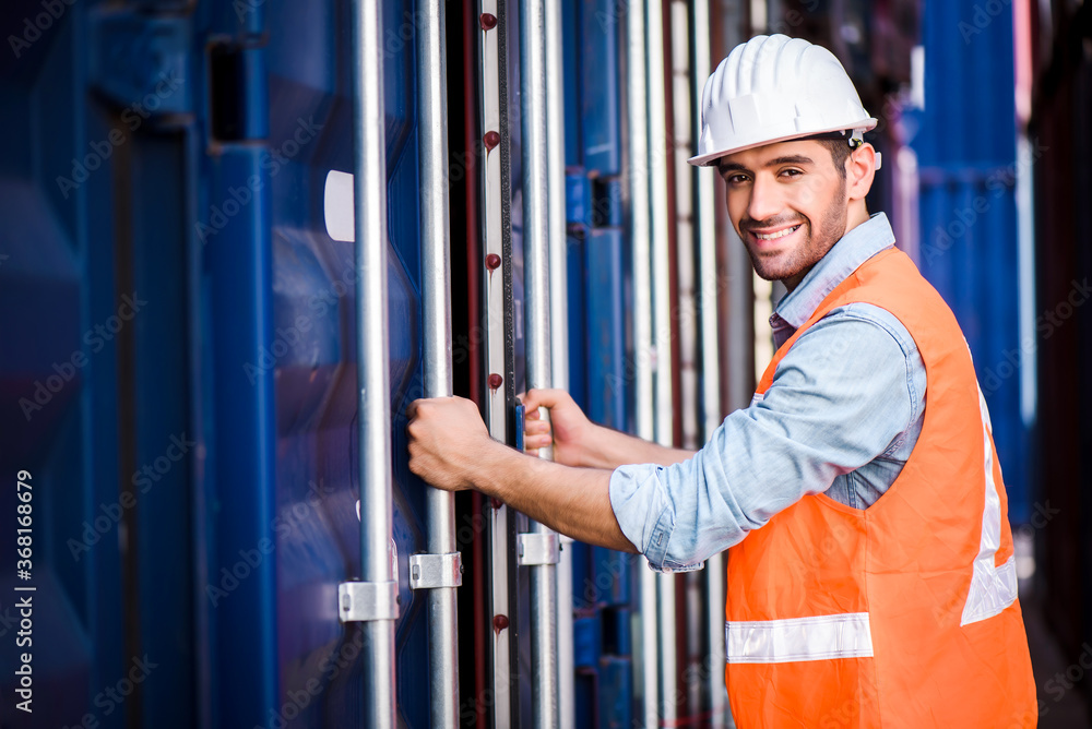 Young confident Caucasian man engineer standing with box container background and check for control loading containers box from Cargo freight ship for import and export, transport Young confident Caucasian man engineer standing with box container background and check for control loading containers box from Cargo freight ship for import and export, transport