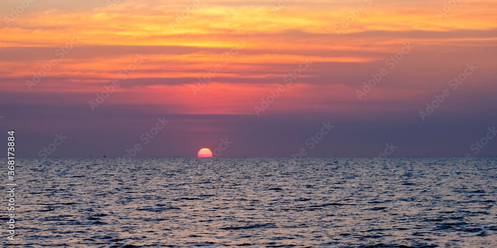 Sunset over the ocean Peaceful seascape. Beautiful cloudy sky over calm sea with sunlight reflection. Copy space banner.