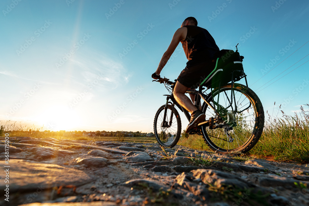 back view of a man with a bicycle against the blue sky. cyclist rides a bicycle.